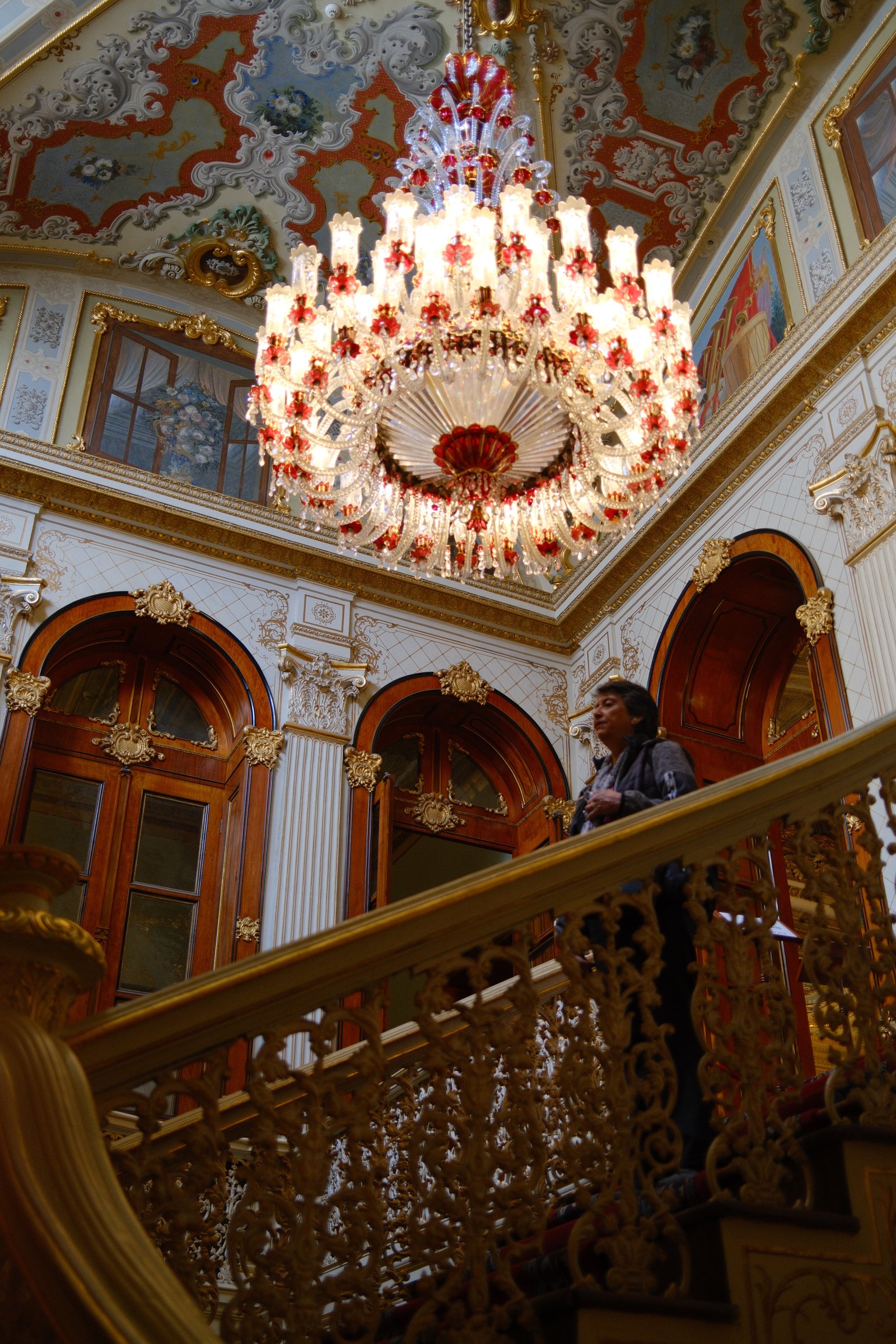 A closer angle on the same chandelier, mirrored wall panels and a visitor in frame.