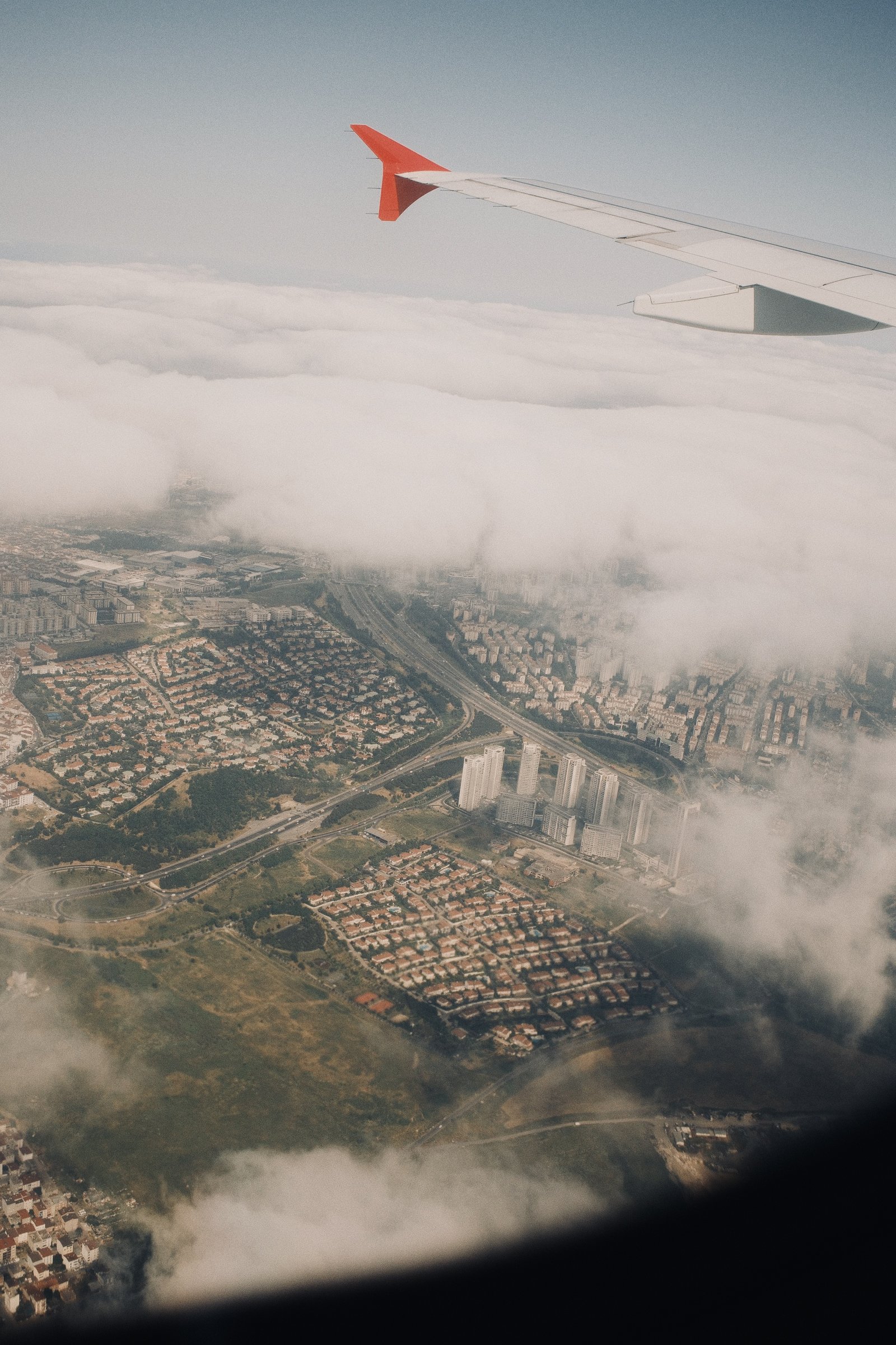 A plane wing over a cloud layer, the city visible in patches below on the way out of Istanbul.
