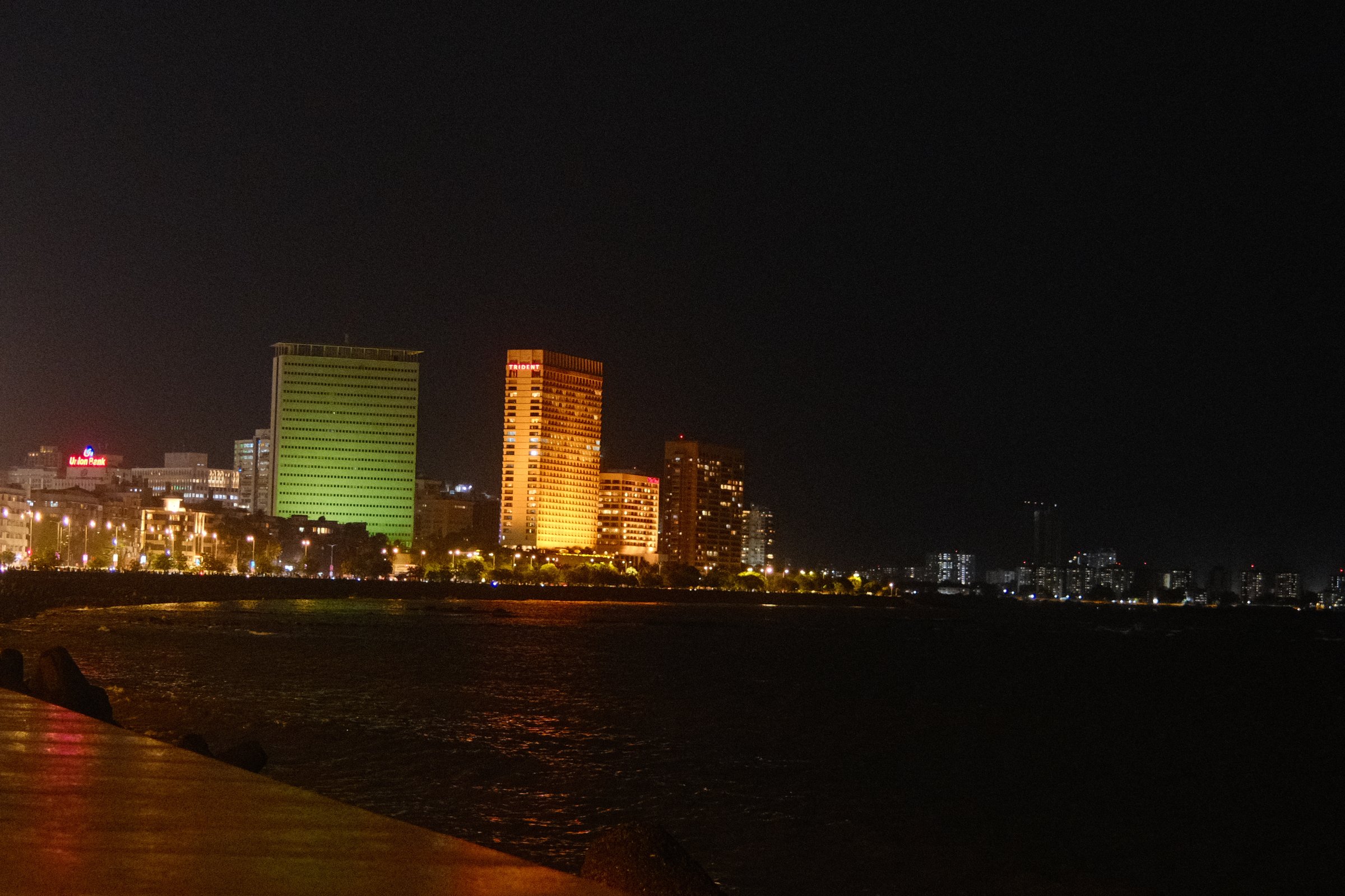 Mumbai's skyline lit up at night, seen across the water from Marine Drive.