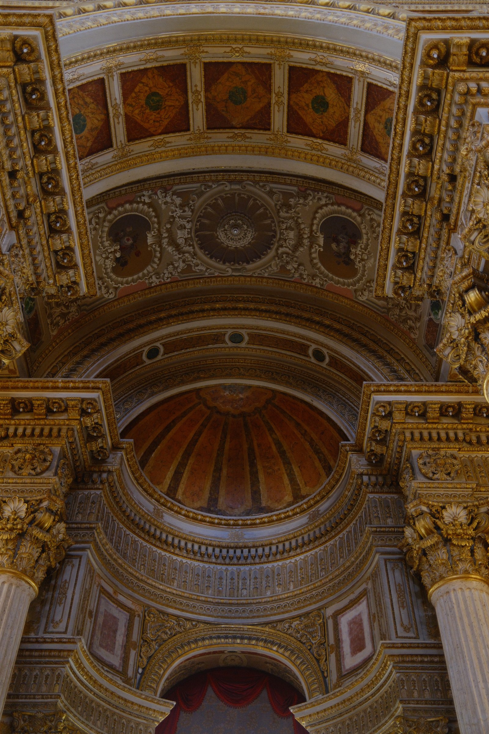 An ornate gold-leafed dome and painted ceiling panels inside Dolmabahce Palace.